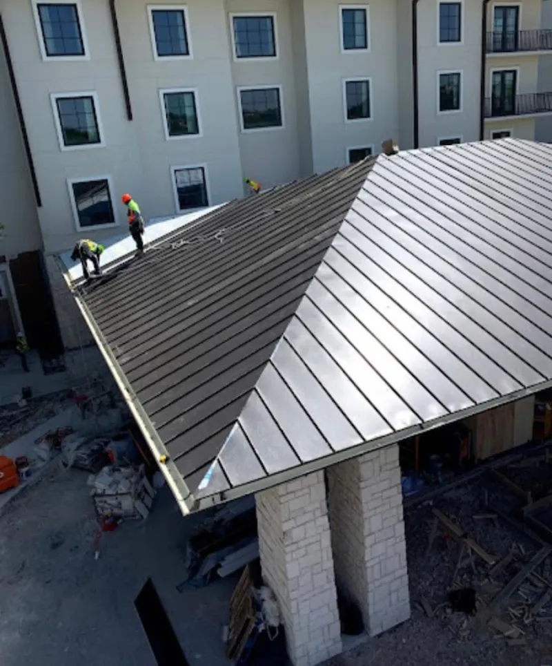 Crew installing standing seam metal roof panels on a commercial project in West Memphis